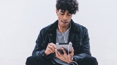 Yakışıklı yeniyetme adam şık kıyafetler giyip şehirdeki şehir merdivenlerinde dinleniyor ve favori müzik podcast 'inin ses kitaplarıyla uygulama yüklemek için boş zaman harcamasını dinliyor.