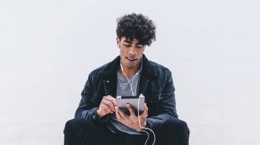 Yakışıklı yeniyetme adam şık kıyafetler giyip şehirdeki şehir merdivenlerinde dinleniyor ve favori müzik podcast 'inin ses kitaplarıyla uygulama yüklemek için boş zaman harcamasını dinliyor.