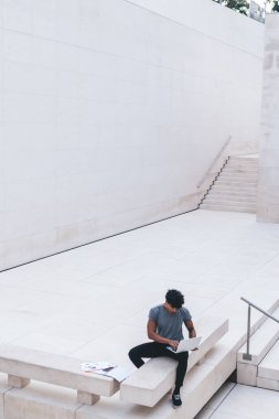 Beyaz iş merkezindeki belgelerin yanında dizüstü bilgisayar kullanarak çalışan üst düzey etnik erkek çalışanlardan.