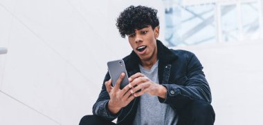 Latin milenyum adamı çek hesabı bakiyesi için mobil bankacılık uygulaması kullanıyor, modaya uygun giyinen hippi adam cep telefonu uyarısı ile ilgili hayret verici bir mesaj alıyor.