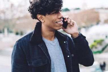 Gülümseyen Afrikalı yakışıklı, kıvırcık saçlı, şık elbiseli, telefonda konuşan, bulanık arka planda duran...