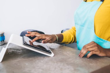 Sarı tişörtlü ve turkuaz önlüklü Afrikalı işçiler hamur işi dükkanının tezgahındaki tablet üzerinde hesap yapıyorlar.