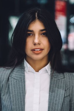 Resmi giyinmiş genç ve güzel bir bayan. Saçları dökülmüş. Geceleri sokakta dikilip bulanık arka plandaki kameraya bakıyor.