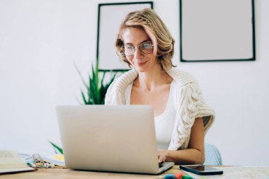 Klasik gözlüklü, gülümseyen kadın, sosyal medya sitelerinde dosya indirmek için bilgi arıyor. Gözlüklü mutlu kadın internet bağlantısını online sohbet için kullanıyor.