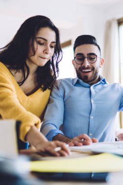 Projeyi düşünen düşünceli uzaktan kumandalı işçiler, evde çözümleri düşünürken neşeli adamla notları kontrol eden bir kadın.