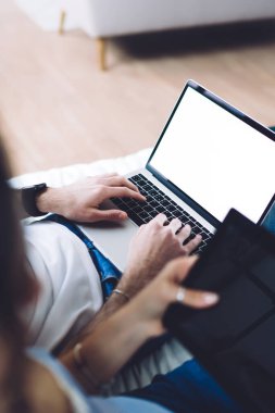 Yukarıdan bakıldığında, günlük giysiler içinde tanınmayan insanların yatakta otururken, dijital tablet ve dizüstü bilgisayar kullanarak vakit geçirdikleri görülüyor.