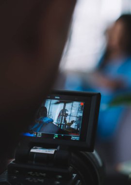 Görüntünün yumuşak odağı profesyonel kameranın ekranında bulanık arka planda parlak mavi giyim siyah kadın modelini çekerken