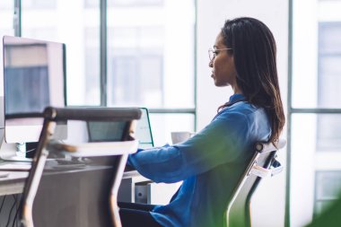 Bilgisayarda tek başına oturan ve hafif işyerinde proje geliştiren siyah sorumlu yöneticinin yeşil santrali üzerinden yan görünüm