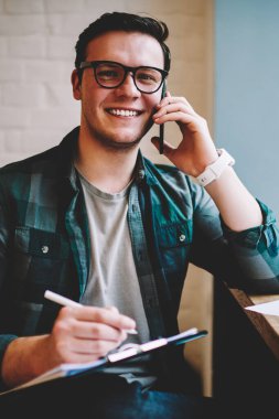 Bilgi eğitim, başarılı hipster adam alan coworking uzak iş üzerinde makale yazma sırasında telefon görüşmesi için dikkat çeken ise telefon danışmanlık ile neşeli adam portresi memnun