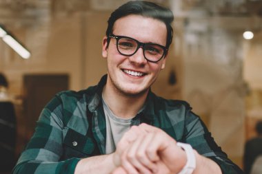 Dijital kol saati öğrenme kafe iç zamanında kontrol gözlük neşeli hipster adam portresi, genç erkek giyilebilir bilgisayar ile memnun mutlu olsun yeni ileti uyarısı