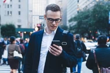 Modern stil kısa saçlı resmi adam mobil uygulamaları kontrol ediyor modern şehrin merkezinde yaya geçidinde duruyor bulanık bir geçmişi var.