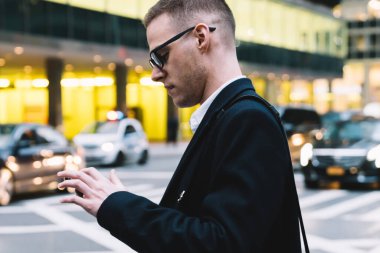 Ciddi ve odaklanmış bir erkek işçinin yol kenarında duran ve sosyal medyada bulanık arka planda sohbet eden