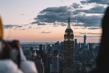 Gece vakti gökdelenlerin New York 'u keşfederken, kış kıyafetleri içinde gökdelenlerin fotoğrafını çeken gezginin arka görüntüsü.
