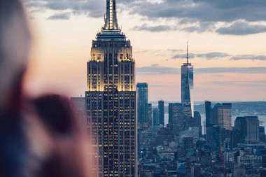Gece vakti gökdelenlerin fotoğrafını çeken erkek gezginin New York 'u keşfederken görüntüsü. Ünlü Empire State Binası 'nı gezmek. Sahne şehir manzarası
