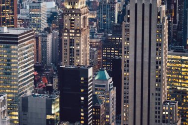 Manhattan 'ın çeşitli yüksek gökdelenlerinin gökdelenlerinin gökdelenleri. New York' ta akşam saatlerinde pencereleri açık olan binalar. Metropolis 'in gece hayatı, ofisler ve gayrimenkul. Şehir merkezindeki yapılar