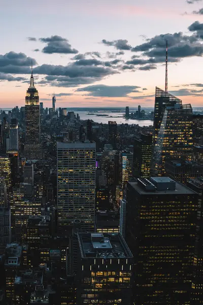 Manhattan 'ın çeşitli yüksek binalarının ve gökdelenlerinin gökdelenlerinin gökdelenleri New York şehrinde akşam gökyüzü ve bulutların arka planında yer alıyor.