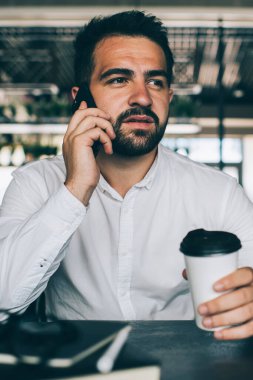 Kafkasyalı, sakallı, cep telefonuyla konuşan, elinde tek kullanımlık bardakla gezen, düşünceli, kendine güvenen, kafede oturan akıllı telefon görüşmesi yapan, iş hakkında konuşan hippi.