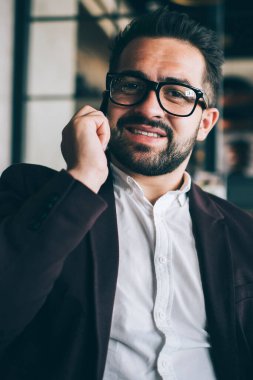 Neşeli sakallı gururlu CEO 'nun portresi akıllı telefondan konuşuyor kahve molası sırasında sohbetin keyfini çıkarıyor, resmi giyinmiş zengin iş adamı kameraya bak, kullan-at fincanı çekiyor.