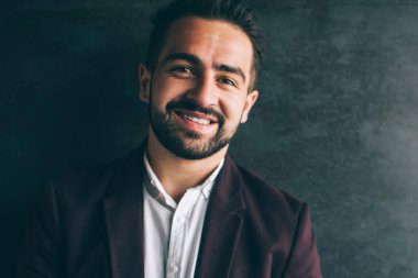 Resmi kıyafetli Kafkas işadamı şık bir ceket giymiş kameraya bakıyor. Promosyon arka planında hücresel duruyor. Mutlu bin yıllık erkek girişimci portresi.