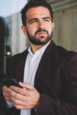 Resmi kıyafetli düşünceli beyaz bir adam elinde akıllı bir telefonla mesaj göndermeyi planlıyor. Moda ceketli ciddi bir erkek cep telefonu kullanıyor ve dışarıda dolaşmak için 4G kullanıyor.