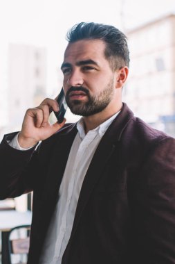 Açık havada cep telefonuyla konuşan düşünceli beyaz girişimci, modaya uygun ceketli zengin bir erkek iş konuşmaya odaklanmış 4G kullanarak akıllı telefon görüşmesi yapıyor.
