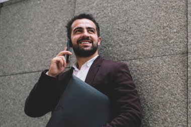 Şık ceketli, zengin, beyaz bir adam gezen, gülümseyen ve gülümseyen bir erkek olarak gezen cep telefonuyla kariyer yapmaktan memnun. Şehir merkezlerinde yapılan akıllı telefon konuşmaları sırasında gülümsüyor.