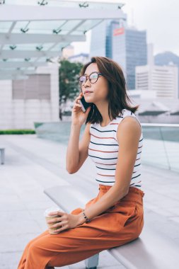 Çekici Çinli kadın turistin kahve ile kentte dinlenmesi, konuşma ve iletişim için mobil çağrı alması, modern teknoloji kavramı ve Z jenerasyonu