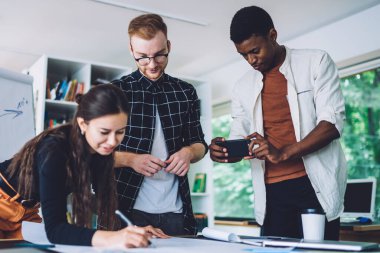 Üniversitenin modern atölyesinde çeşitli milenyum tasarım projeleri oluşturan zeki iş arkadaşlarıyla işbirliği yaparken, Afrika kökenli Amerikalı erkek çalışanın taslak çizimi