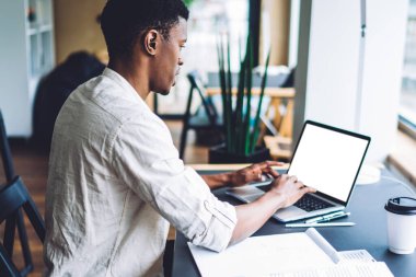 İnternet reklamları için boş ekranı olan modern dizüstü bilgisayarda uzaktan çalışan koyu tenli erkek serbest yazar, bin yıllık öğrenci netbook 'tan gelen web bilgileriyle sınava hazırlanıyor