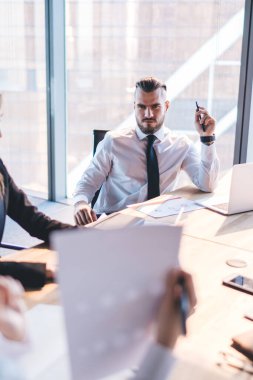 Resmi olarak resmi görevli kişiler, modern şehir ofisindeki konferans masasında otururken kağıt tartışması ve dizüstü bilgisayar ve tablet üzerinde gezinme giyerler.