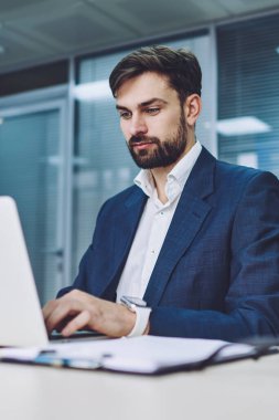 Resmi olarak konsantre olmuş erkek avukat, konferans odasında kablosuz internet bağlantısı, iş adamları ve teknoloji kavramı olan modern laptop cihazını kullanırken internet sitesinde rezervasyon biletleri takıyor.