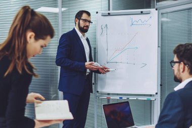 Profesyonel ekonomist, proje için grafik ve bilgi ile beyaz yönetim kurulunun yanında duruyor. Başarılı iş adamları birlikte iş birliği yapıyor ve şirkette sorunları birlikte çözüyorlar.