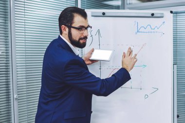 Akıllı erkek işadamı, büyüyen şirketler hakkında ana bilgilere ulaşmak için grafiği ters çevirme çizelgesinde ve akıllı telefondan gelen boş ekran alanındaki bilgileri kullanarak zaman harcıyor.