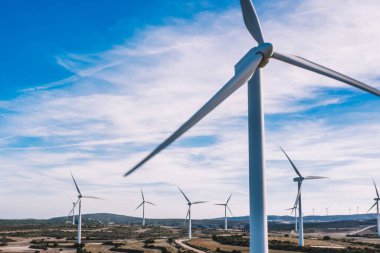 Kuşlar rüzgar enerjisinden yeşil enerji kaynakları üreten yel değirmenleri istasyonunu tarımın engin alanlarında görüyorlar. Çayırlarda dönen türbinlerle alternatif elektrik üretimi