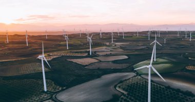 Kırsal tarım ortamında eko kaynaklarından alternatif temiz yeşil enerji üreten dönen pervaneli yel değirmenlerinin hava görüntüsü. Kuş bakışı türbinlerin elektrik üreten hattına bakıyor.