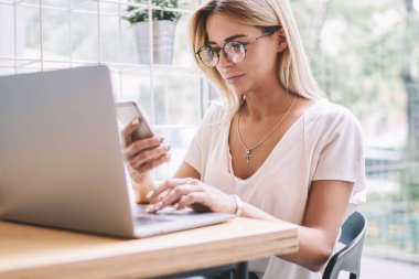 Modern teknolojiler hakkında içerik web blog mesajları kontrol ederken sosyal ağdan takipçisi göz koruma yazarak cevap sağlamak için trendy Gözlük Genç çekici hipster kız