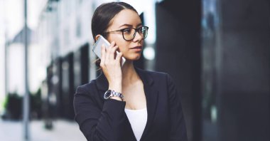 Güvenli kadın banker kentsel ayar ayakta iken hesap dengesi hakkında Detayları tartışmak için operatör ile konuşurken, optik gözlük uygulama üzerinden akıllı telefon konuşma yapma ciddi kadın