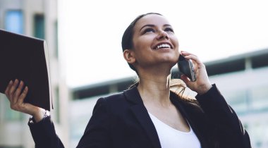 İş ortakları cep telefonu ile arama iyi bir anlaşma yaptıktan sonra heyecanlı şirket etek elbise hissi heyecanlanan kadın girişimci gülümsüyor. İş kadını elde sonra başarı kutluyor