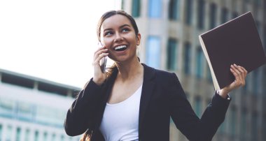 Heyecanlı kadın girişimci cep telefonu ile arayan ortakları ile başlangıç iş projesinin ayrıntılarını tartıştıktan sonra heyecanlı hissediyorum. Başarılı hayran işkadını iş başarısı kutluyor