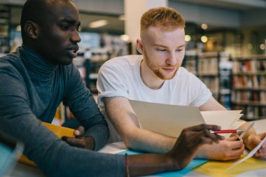 Çok ırklı odaklı yöneticiler günlük kıyafetleriyle notları okurken ofis binasında Joy 'la birlikte çalışıyorlar.