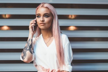 Şık giyinmiş, elinde not defteri olan genç bir hippi kadın. Şehir merkezinde boş zamanlarında cep telefonu iletişimine odaklanmış. 4 g 'lik internet kullanan güzel bir genç.