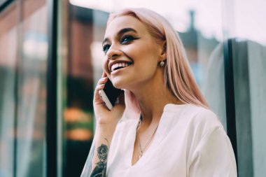 Neşeli bir kadın milenyumu, elinde büyük bir dövmeyle en iyi arkadaşına telefon ediyor, cep telefonunda gezinen bağlantıyı kullanıyor, neşeli bir hippi kız gülümsüyor ve telefonla konuşuyor.