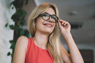 Tatmin olmuş genç sarışın kadın çalışanın modern kafede çalışırken ve masada otururken bardaklara dokunması.