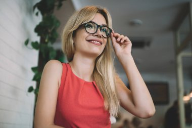 Tatmin olmuş genç sarışın kadın çalışanın modern kafede çalışırken ve masada otururken bardaklara dokunması.