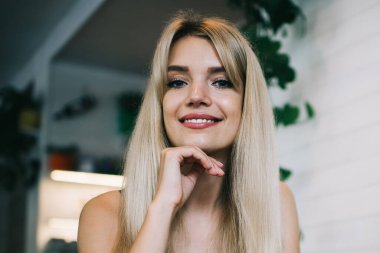 Akıllı saat takan mutlu modern kız öğrenci laptop ve akıllı telefonla masada oturuyor ve kafede boş zaman geçirip internette gezinirken kameraya bakıyor.