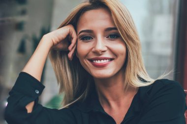 Sarışın, güzel beyaz kadın portresi. Şehir bankında dinleniyor ve kameraya bakıyor. Yüzünde sevimli bir gülümsemeyle.