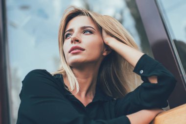 Gösterişli siyah tişörtlü, düşünceli, düşünceli, fikirlerini değiştiren, şehir bankında dinlenirken kaybolmuş, gündelik giysiler içindeki çekici hippi kız.