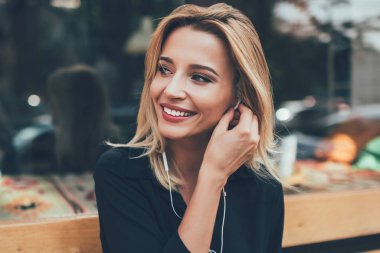 Neşeli, genç ve tatlı bir kız elektronik kulaklıkla müzik dinlerken kentteki bankta dinleniyor. Neşeli, neşeli bir bayan meloman çevrimiçi müzik listesinden şarkılar dinliyor.