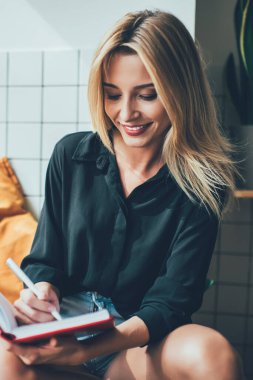 Başarılı kadın, kafede otururken üretken bir gün geçirdiği için mutlu kadın zaman yönetimi kontrol listesi yazıyor, pozitif öğrenci kapalı alanda eğitim alırken ders kitabına not alıyor.