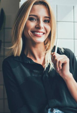 Ders kitabı ve kalemle elinde mutlu bir kız öğrencinin portresi kameraya bakıyor ve gülümsüyor, 20 'li yaşlardaki neşeli hippi kız günlüklerine ilginç anlar yazdığı için günün tadını çıkarıyor.